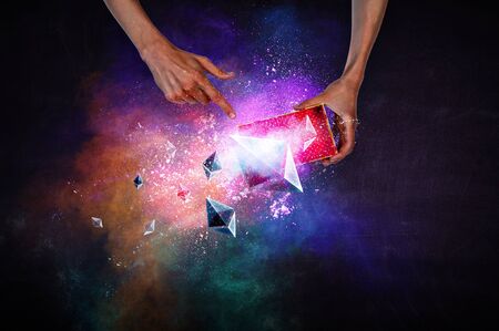 Man`s hands holding a small magic paper box with flying ethereum cymbols, mixed mediaの写真素材