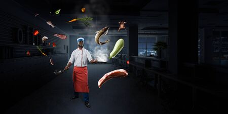 Black man wearing an apron and cooking in action. Mixed mediaの写真素材