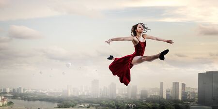 Young and beautiful female dancer in a red dress. Mixed mediaの写真素材