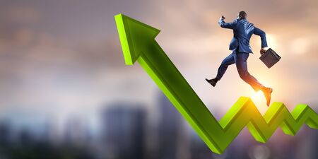 Black businessman running on green zigzag increasing arrowの写真素材