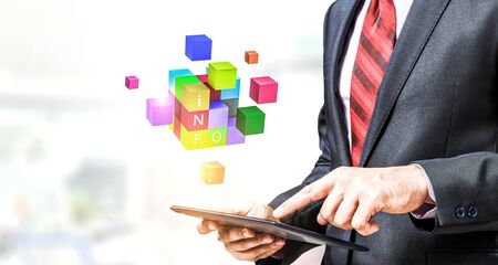 Businessman holding a tabalet with cube puzzle levitating above. Mixed mediaの写真素材