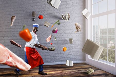 Black man wearing an apron and cooking in action. Mixed mediaの写真素材