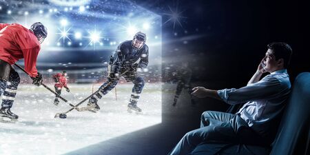Young man watching ice hockey game on TV
