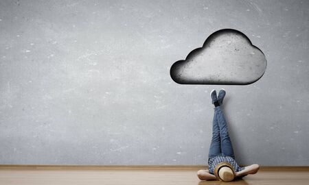 Young man lying on the floor with legs raised up on the wall. Mixed mediaの写真素材