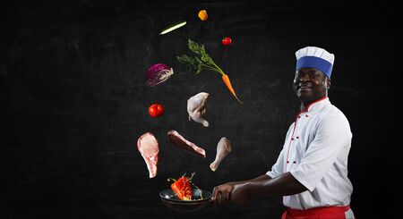 Black man wearing an apron and cooking in action. Mixed mediaの写真素材