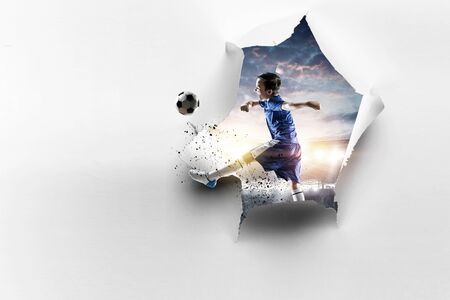 Paper torn hole effect and a kid playing soccer. Mixed mediaの写真素材