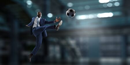 Black businessman in a suit playing footbalの写真素材