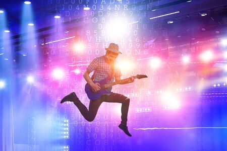 Guitar player jumping with guitar while playing