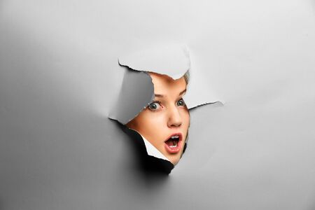 Woman looking out from a hole of torn paperの写真素材