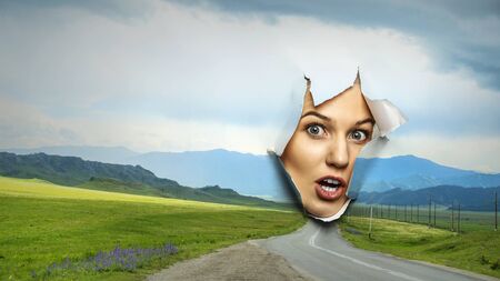 Woman looking through a hole in banner. Mixed mediaの写真素材