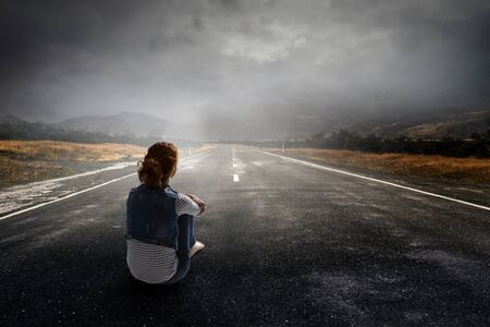 Young woman in casual clothes sitting and hugging kneesの写真素材