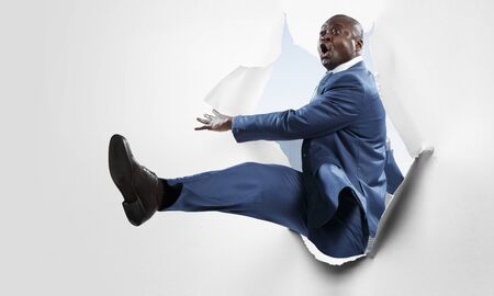 Breakthrough paper hole with a black businessmanの写真素材