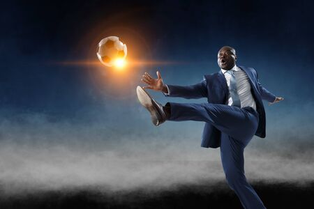 Black businessman in a suit playing footbalの写真素材