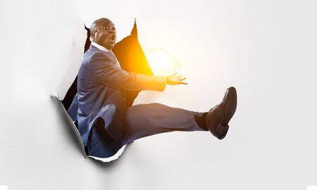 Breakthrough paper hole with a black businessmanの写真素材
