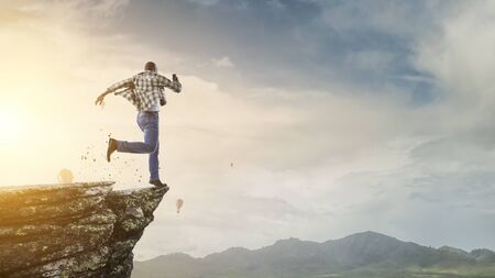 Back view of black man in casual clothes running on the edge of a mountain peakの写真素材