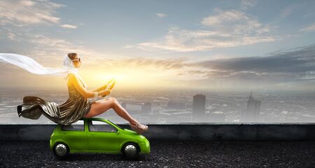 Pretty woman sitting on toy car with steering wheel in hands. Mixed mediaの写真素材
