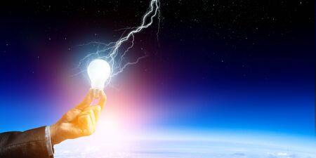 Business hand holding glowing light bulb with lightning