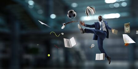 Afroamerican businessman in office kicking ball. Mixed media