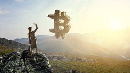 Young businesswoman at top and stone bitcoin symbol. Mixed mediaの写真素材