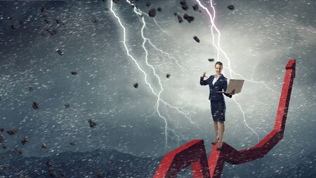 Young businesswoman with laptop in hand doing magic. Mixed mediaの写真素材