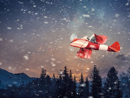 Santa Claus flying in airplane high in sky . Mixed mediaの写真素材