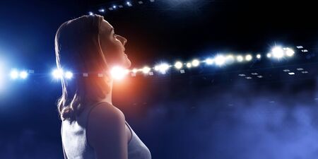 Profile of woman standing in lights of stage