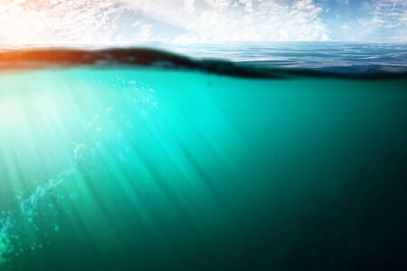 Blue under water at sunset with rays of sunの写真素材