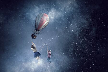 Kid girl flying at night on aerostat balloon. Mixed mediaの写真素材