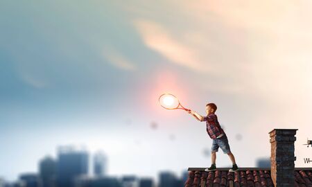 Cute kid boy playing with big tennis racket. Mixed mediaの写真素材