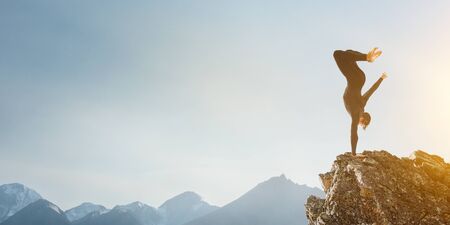 Amazing yoga man doing one handstand on rock edge. Mixed mediaの写真素材