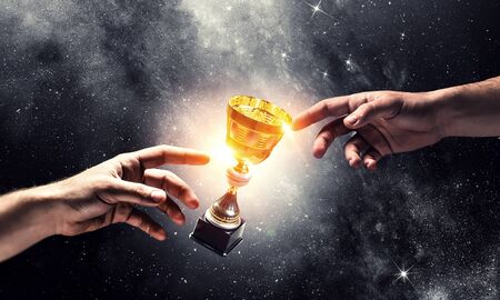 Male hand touching with finger golden cup. Mixed mediaの写真素材