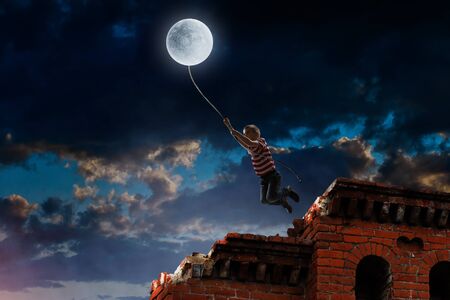 Boy of school age flying moon balloon. Mixed mediaの写真素材