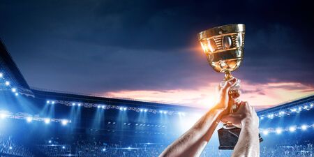 Male hand of athlete holding trophy against stadium lights. Mixed mediaの写真素材