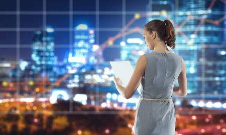 Elegant businesswoman with papers in hands and media infographs. Mixed mediaの写真素材