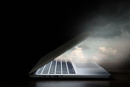 Opened laptop with glowing screen on dark background. Mixed mediaの写真素材