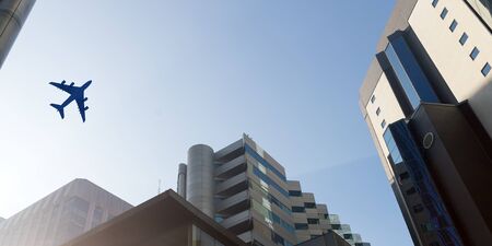 Bottom angle view of airplane in sky over city buildings