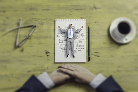 Top view of businessman in miniature lying on notepadの写真素材