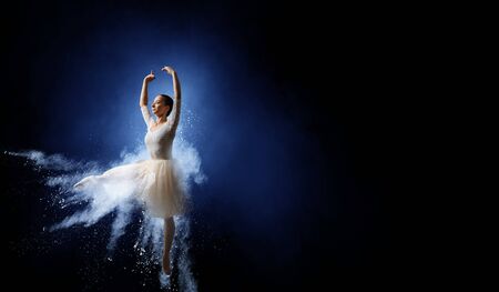 Elegant woman dancer in white dress against dark backgroundの写真素材