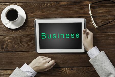 Top view of businesswoman sitting at wooden table and using tabletの写真素材