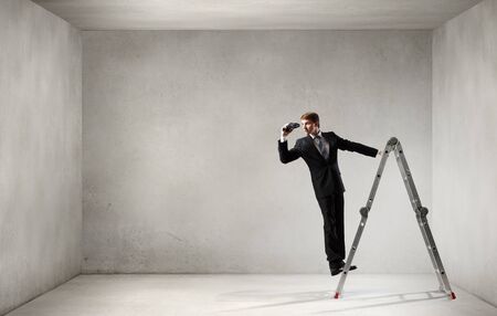 Businessman standing on ladder and looking in binoculars. Mixed mediaの写真素材