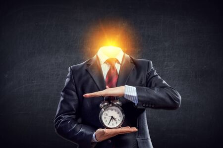 Businessman with light bulb instead of head and clock in hands. Mixed mediaの写真素材