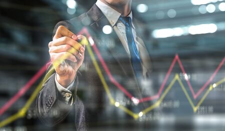 Close of businessman in office drawing media graphs on screen. Mixed media