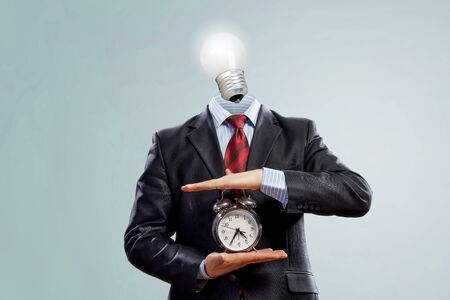 Businessman with light bulb instead of head and clock in hands. Mixed mediaの写真素材