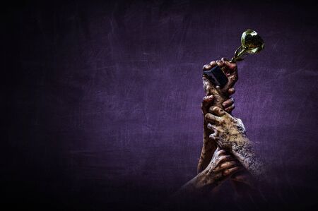 Hand holding up a gold trophy cup against dark backgroundの写真素材
