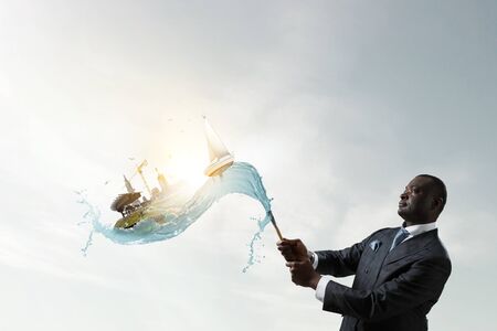 Conceptual image of ambitious and creative businessman in black suit holding paintbrush in handの写真素材