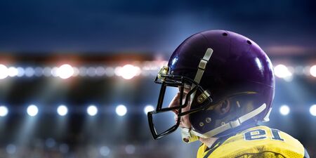 American football player standing on the big modern stadium. Mixed media