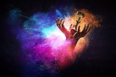 Hands holding champion cup on colourful splashes background. Mixed mediaの写真素材