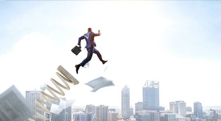 Businessman jumping on springboard as symbol of progress. Mixed mediaの写真素材