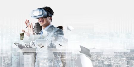 Young businessman wearing VR glasses interacts with cyberspace. Mixed media