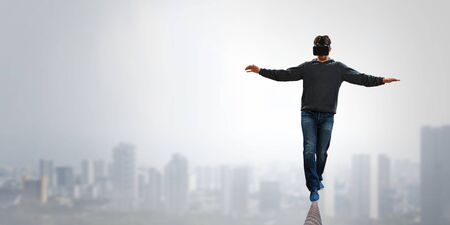 Man wearing virtual reality goggles and balancing on rope. Mixed mediaの写真素材